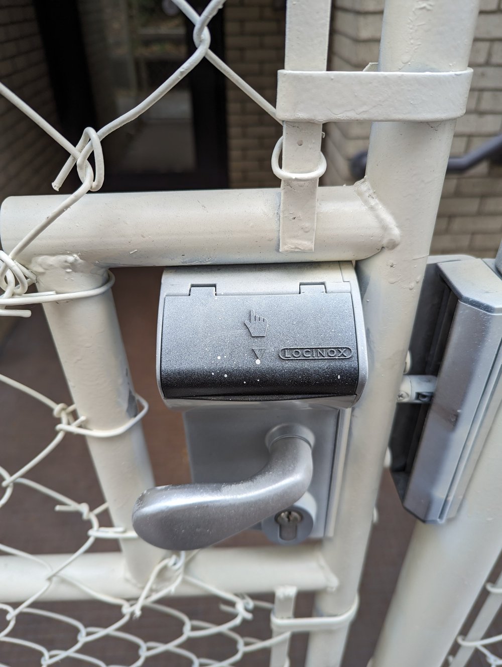 Close-up of the gate latch and a keypad lock with a black cover.